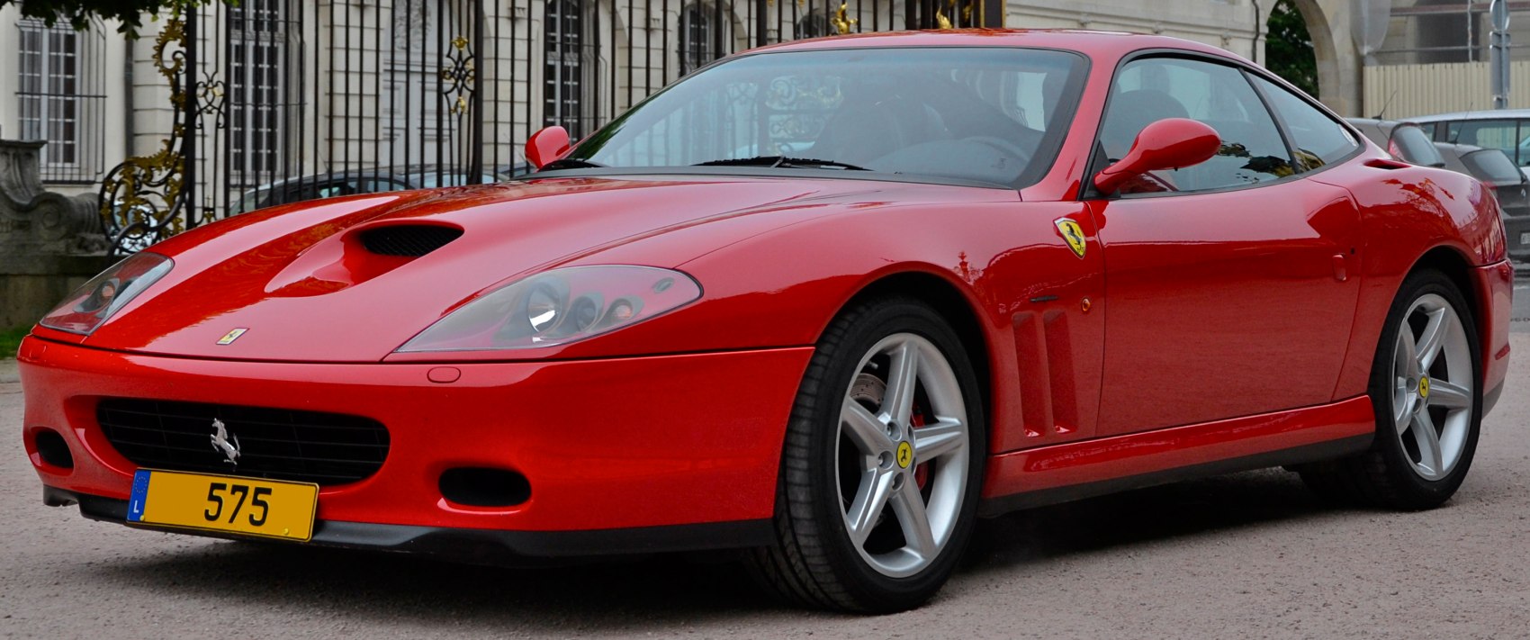 Red sports car featuring hood scoop and five-spoke alloy wheels.