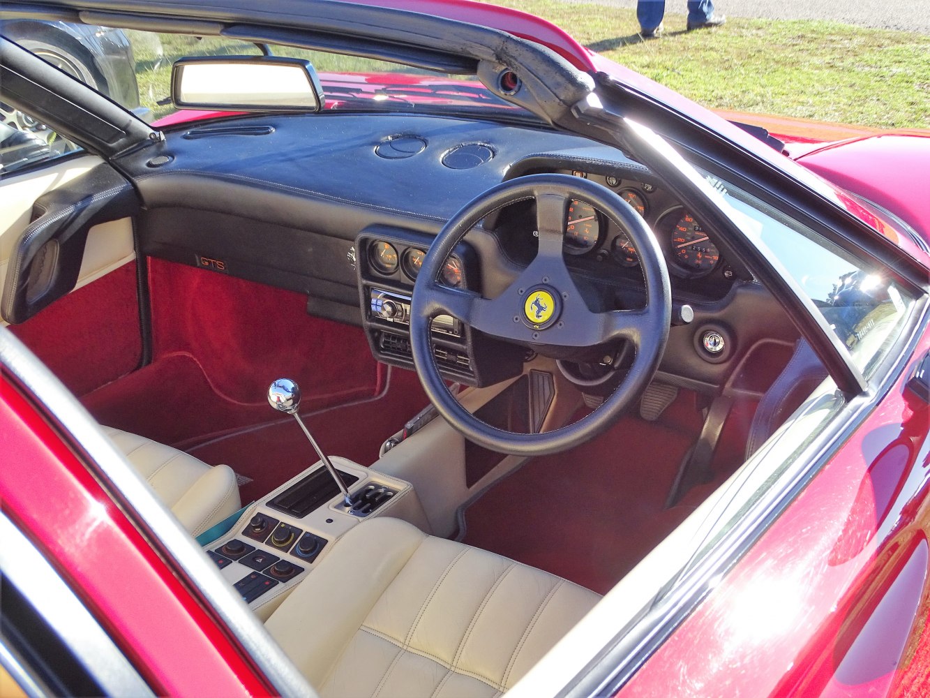 Manual gear stick and three-spoke steering wheel in classic sports car interior