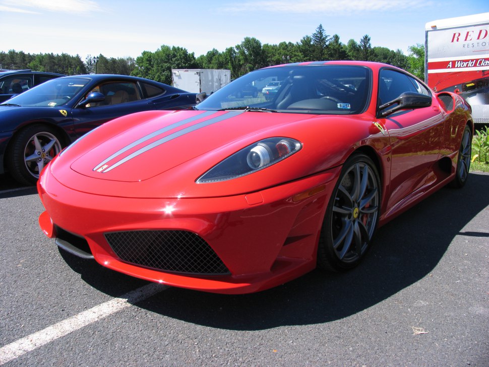 Front view of a red sports car with dual silver racing stripes and aerodynamic features