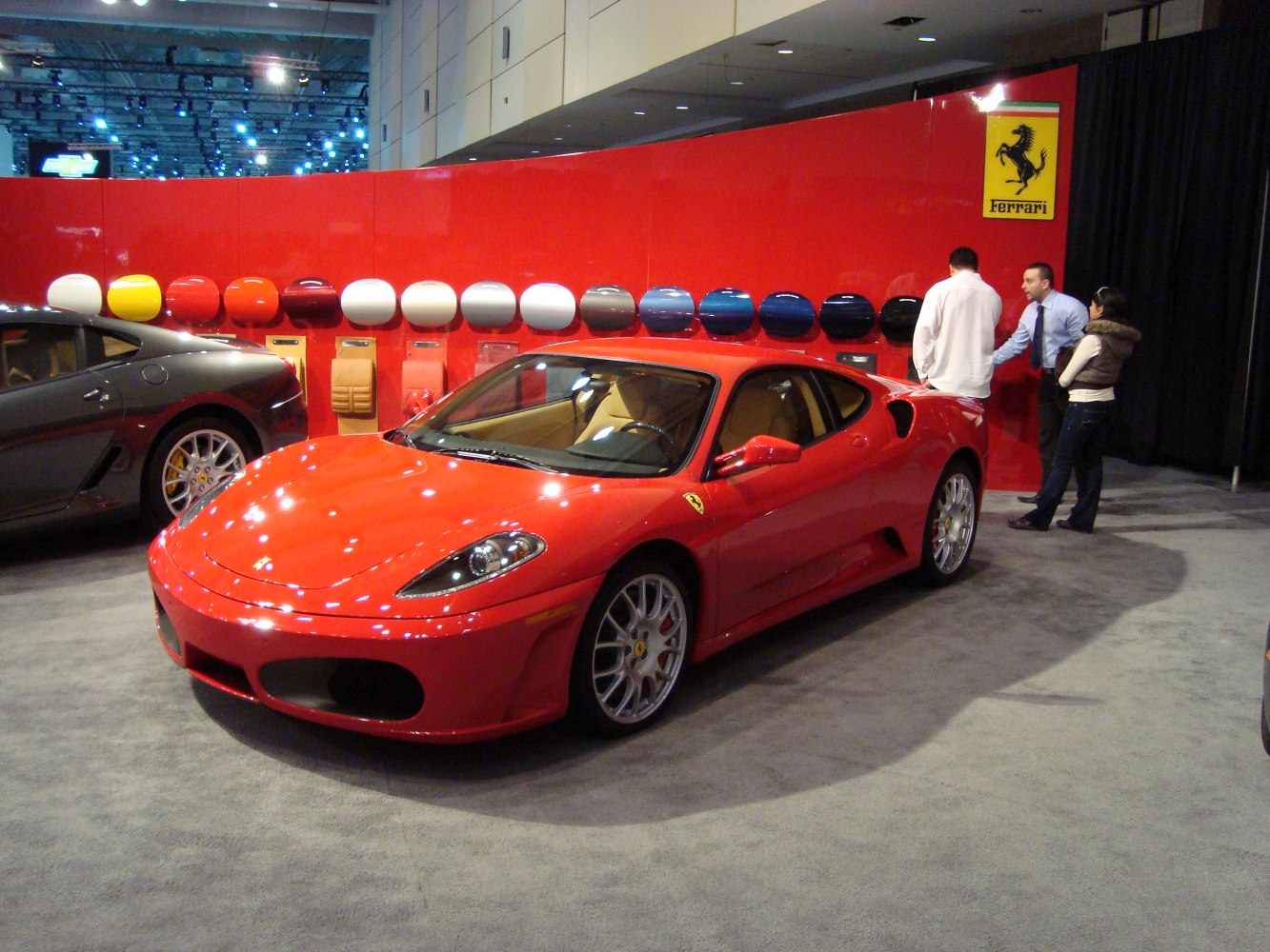 Red sports car front side with alloy wheels near paint and trim samples