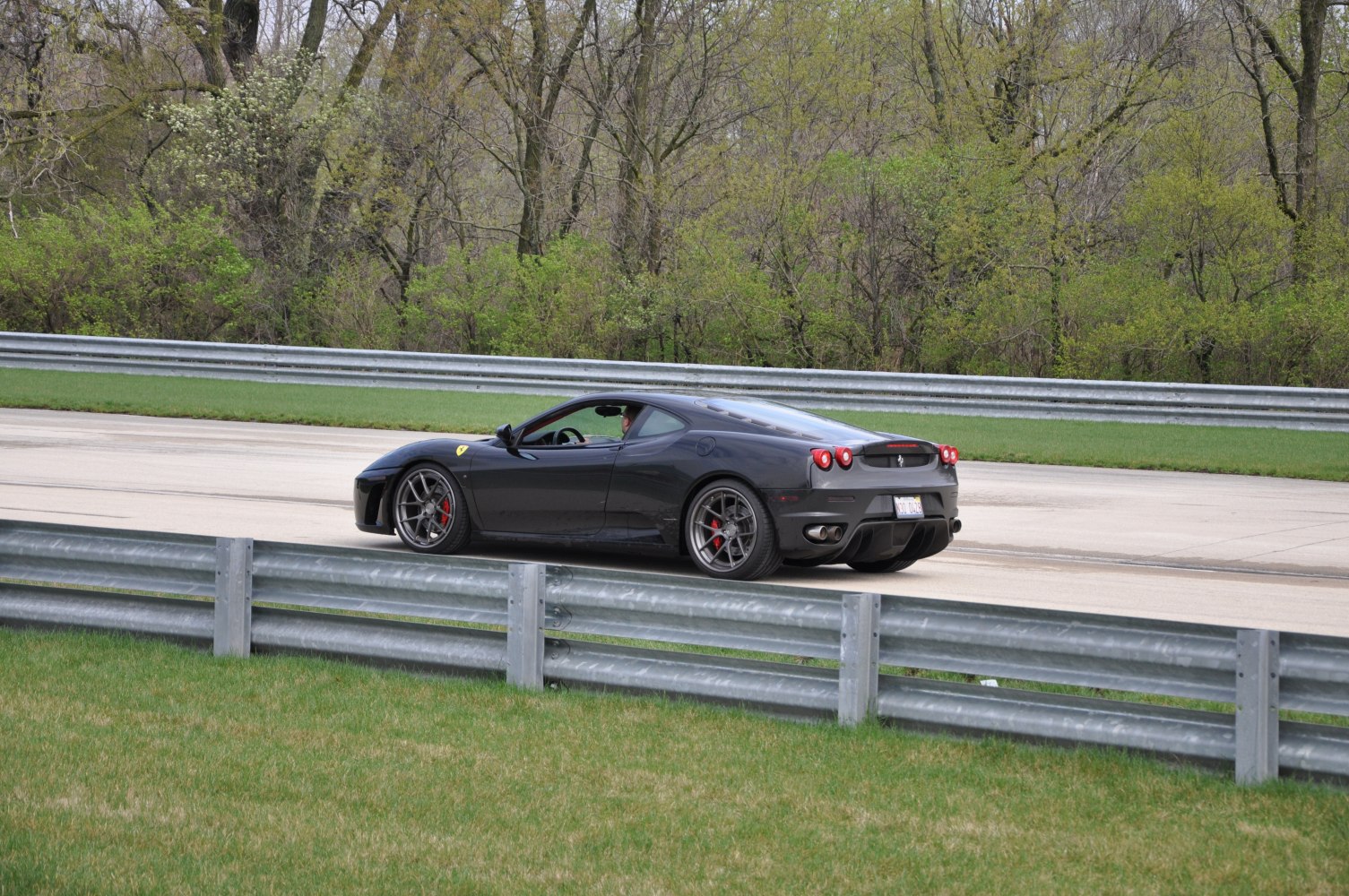 Sleek black sports coupe from rear side on race track with alloy wheels.