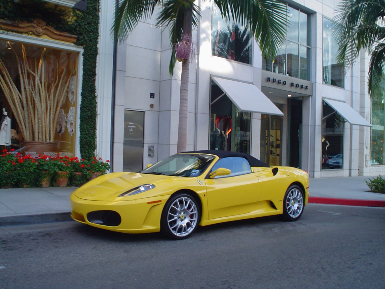 Yellow convertible with black soft top and aerodynamic body parked urban street