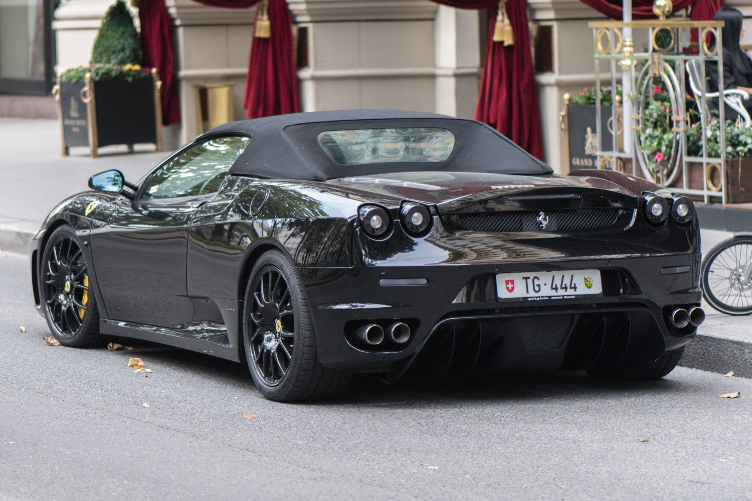 Convertible sports car rear with quad exhaust and black soft top roof