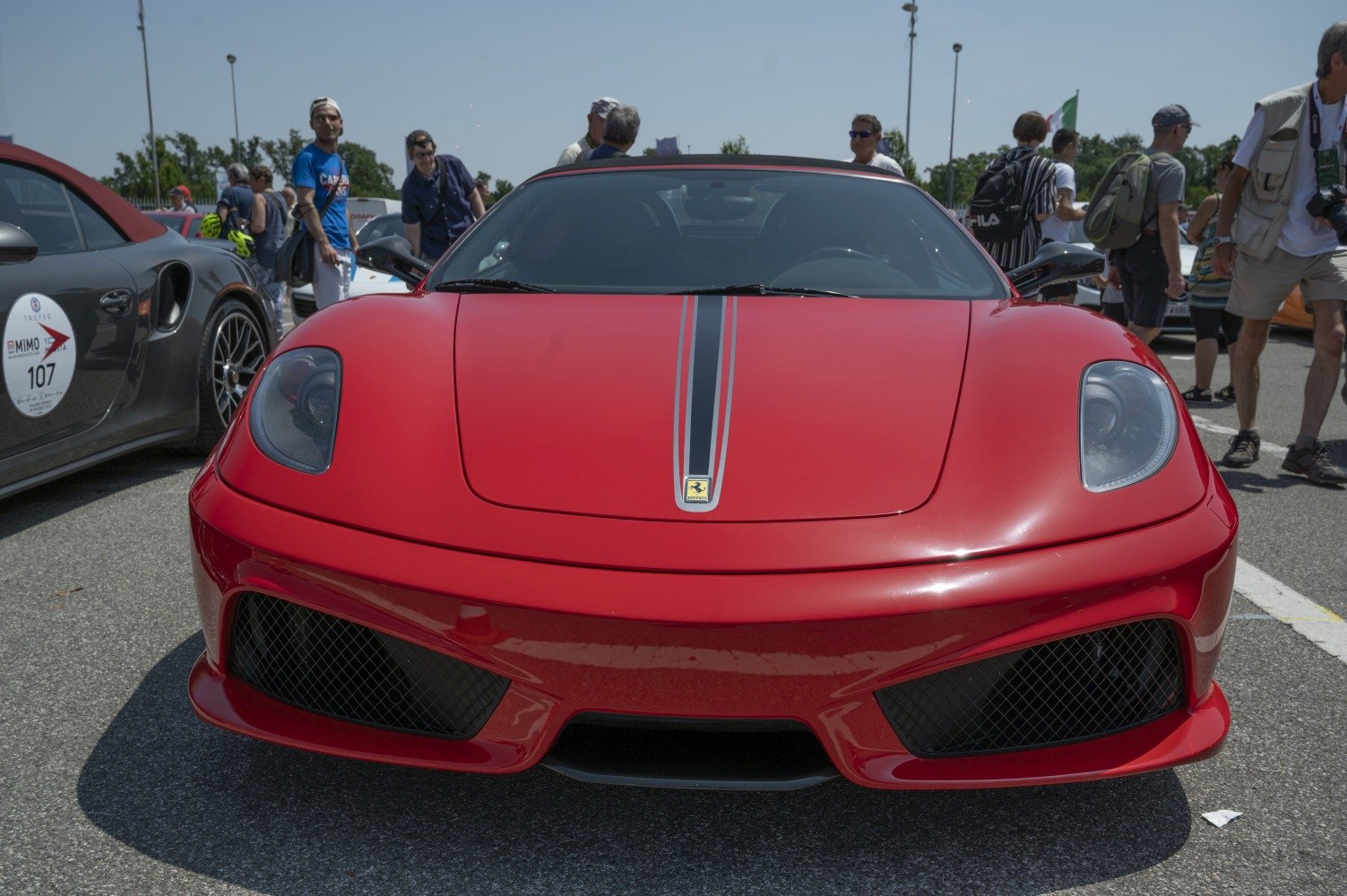Front view of a red sports car with racing stripe and aggressive grille.