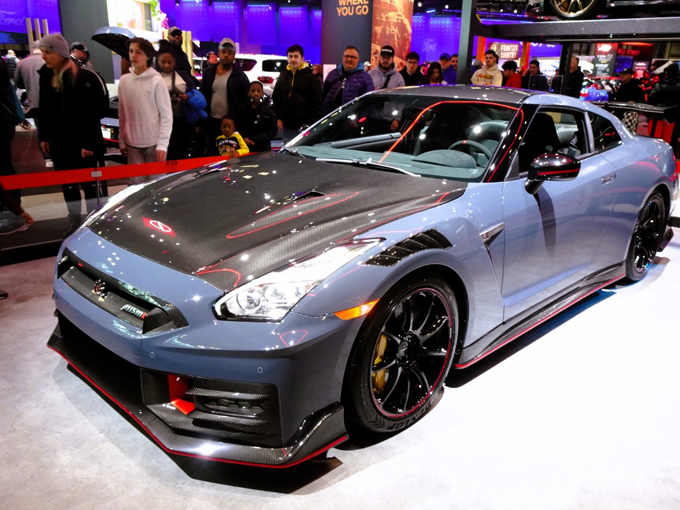 Front three-quarter view of sports coupe with carbon fiber hood and aerodynamic details.