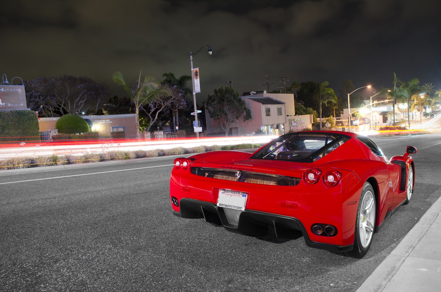 Rear view of a red exotic sports car with aerodynamic design and quad tail lights at night