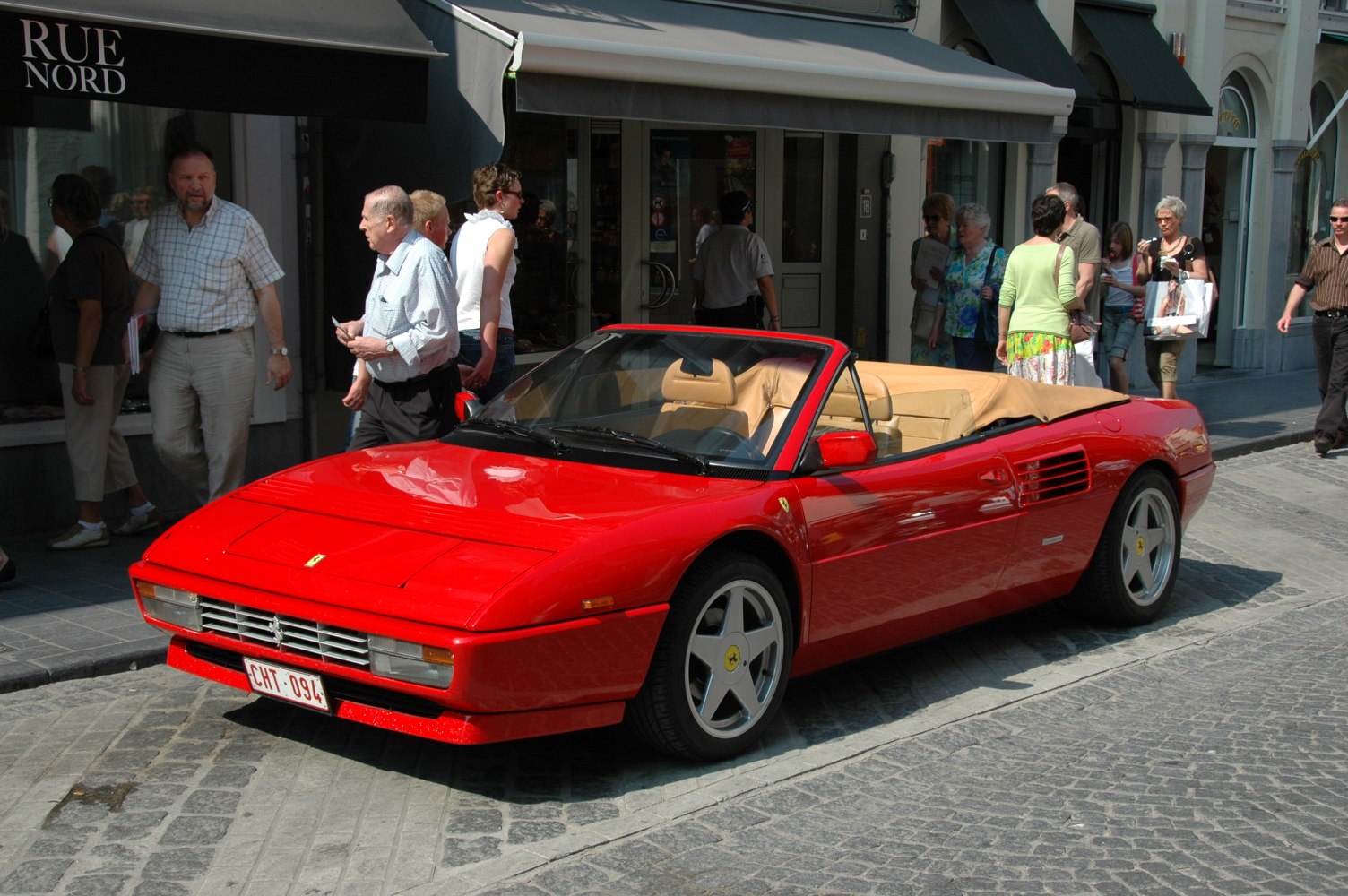 Red convertible sports car with tan leather interior and five-spoke rims
