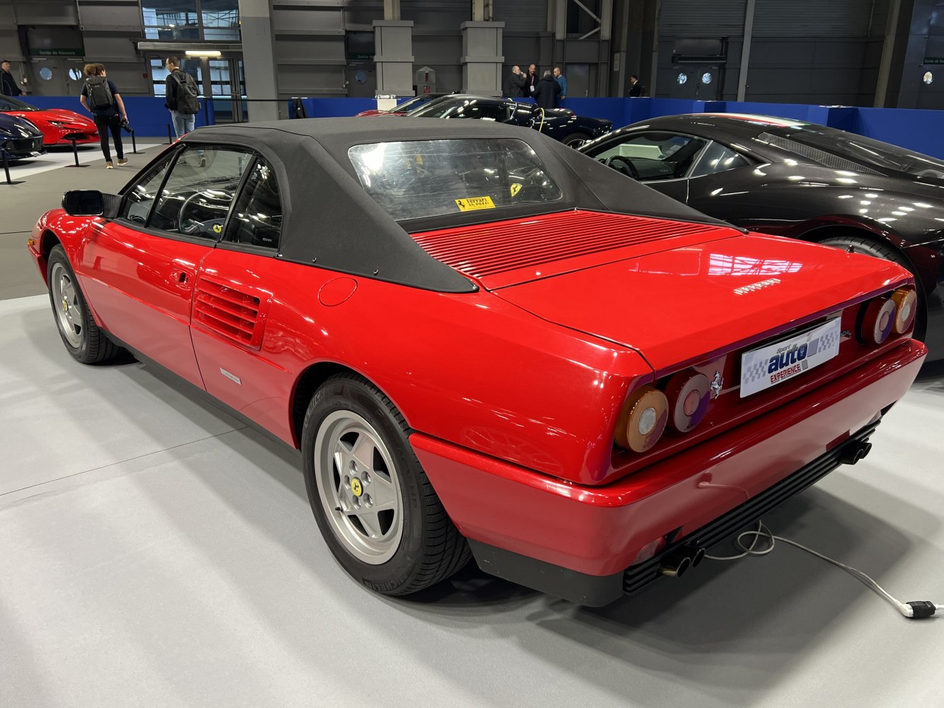 Red convertible with black soft top, rear vents, and alloy wheels