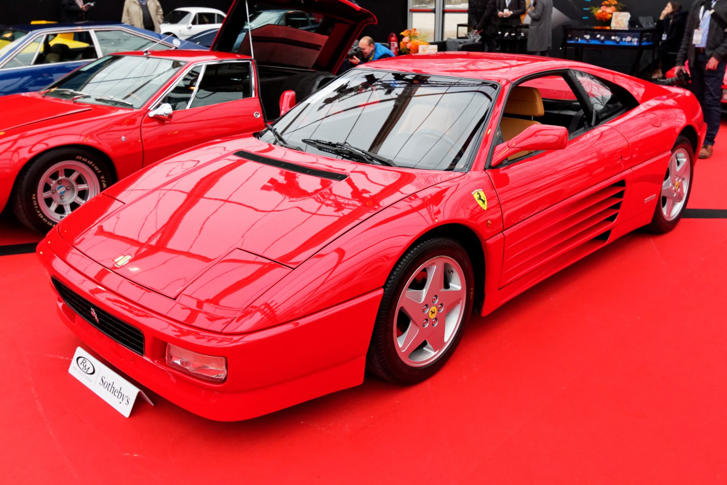 Red mid-engine sports coupe with side louvers and alloy wheels