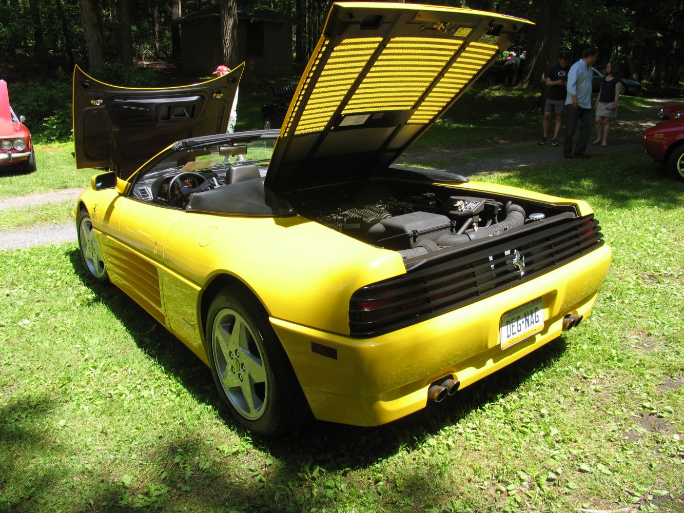 Yellow convertible with open rear engine bay and open driver's door, rear three-quarter view