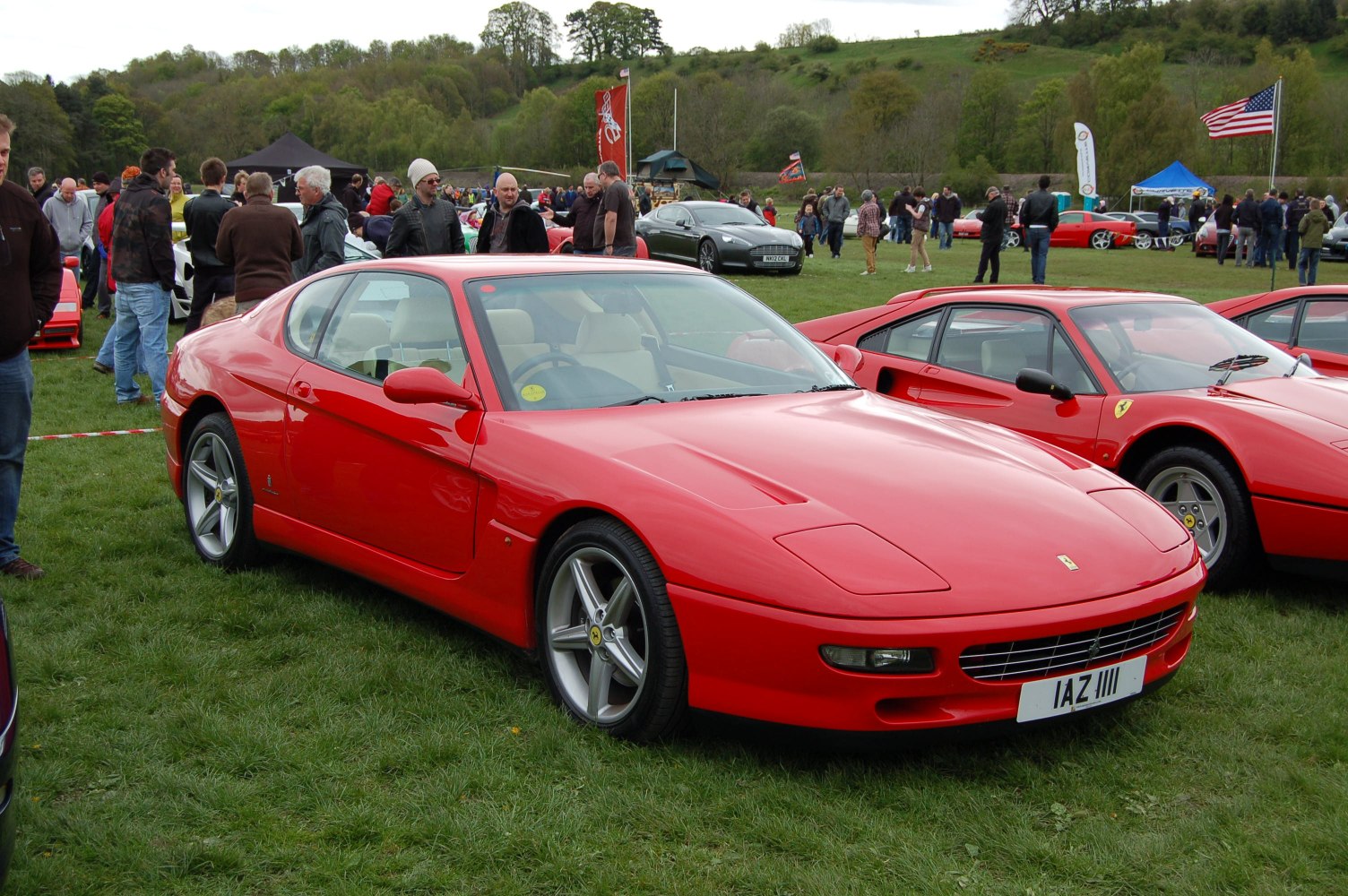 Classic red sports coupe with pop-up headlights on grassy field.