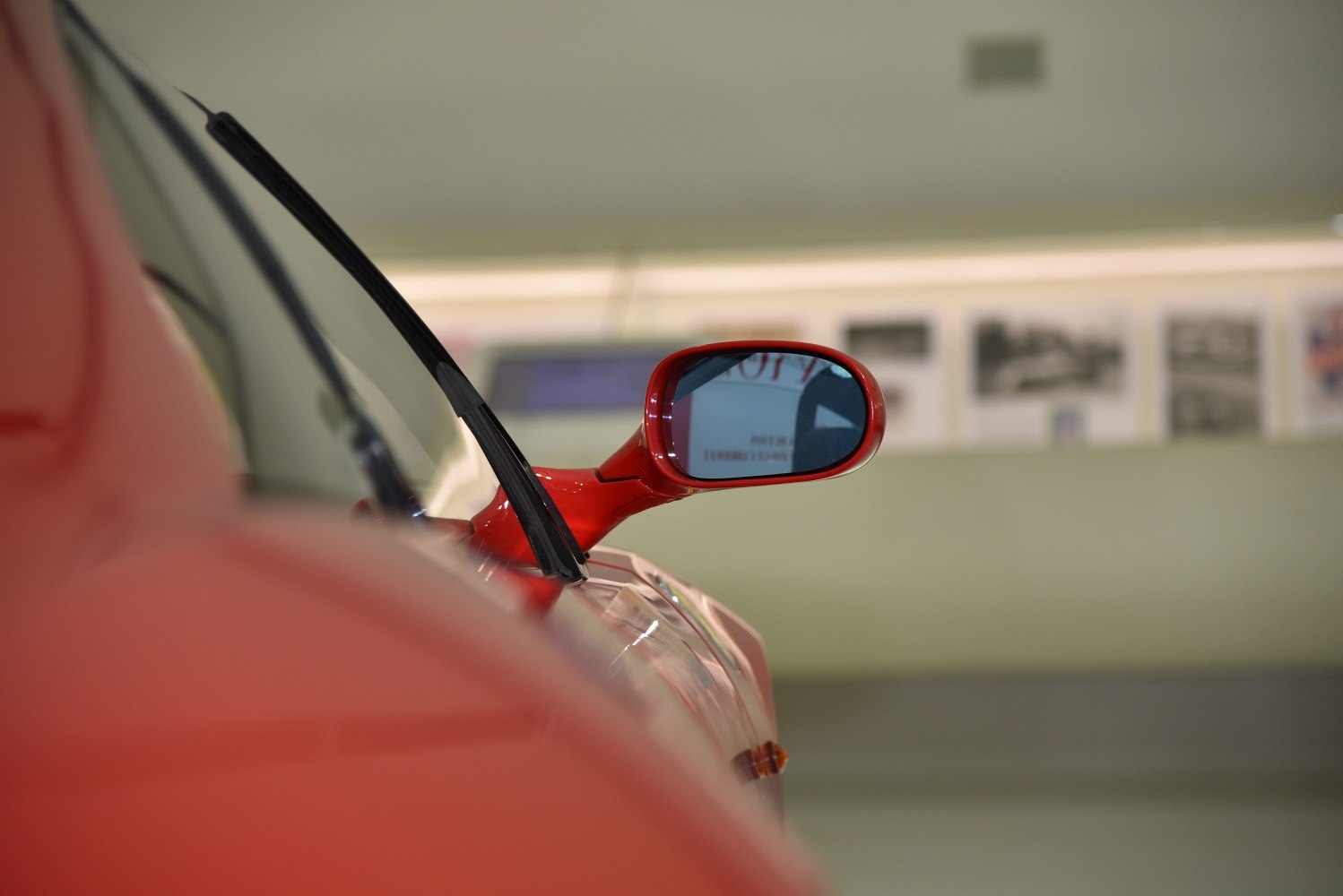 Close-up of red side mirror and windshield wiper on a sports car