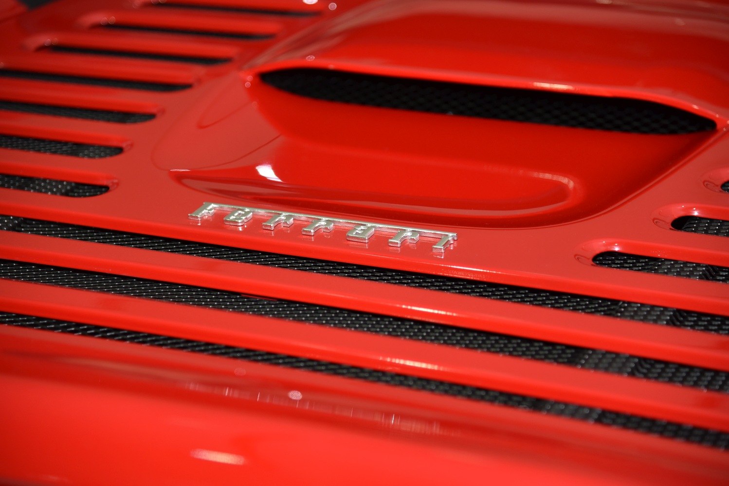 Close-up view of red engine cover with ventilation slots and grille