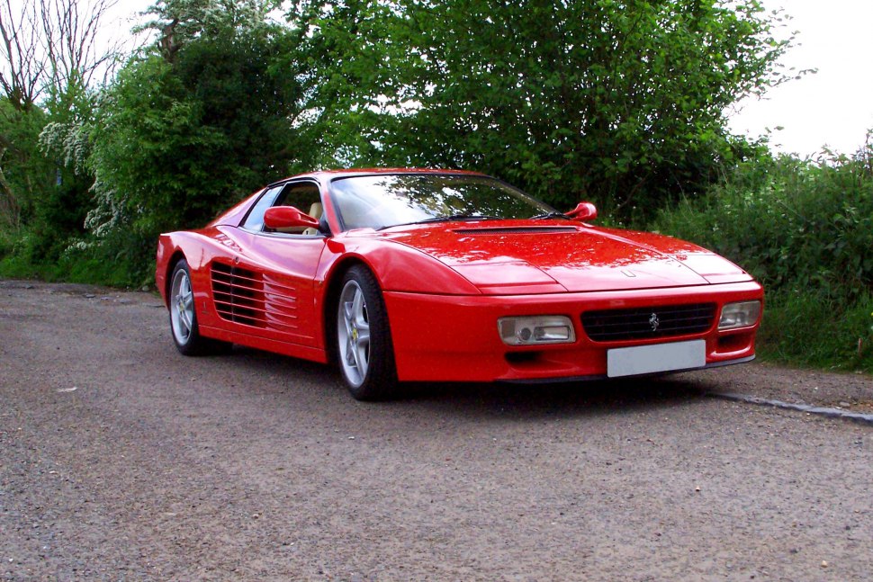 Front-side view of red sports car with side strakes and pop-up headlights