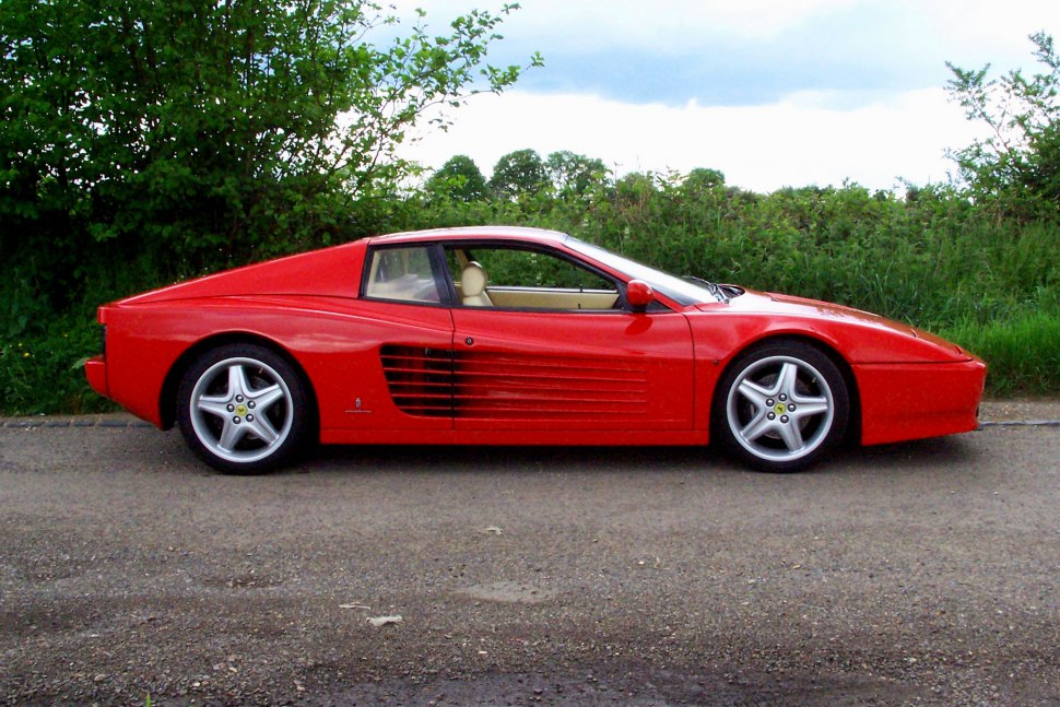 Side profile of a red sports car with horizontal ventilation slats and aerodynamic body.
