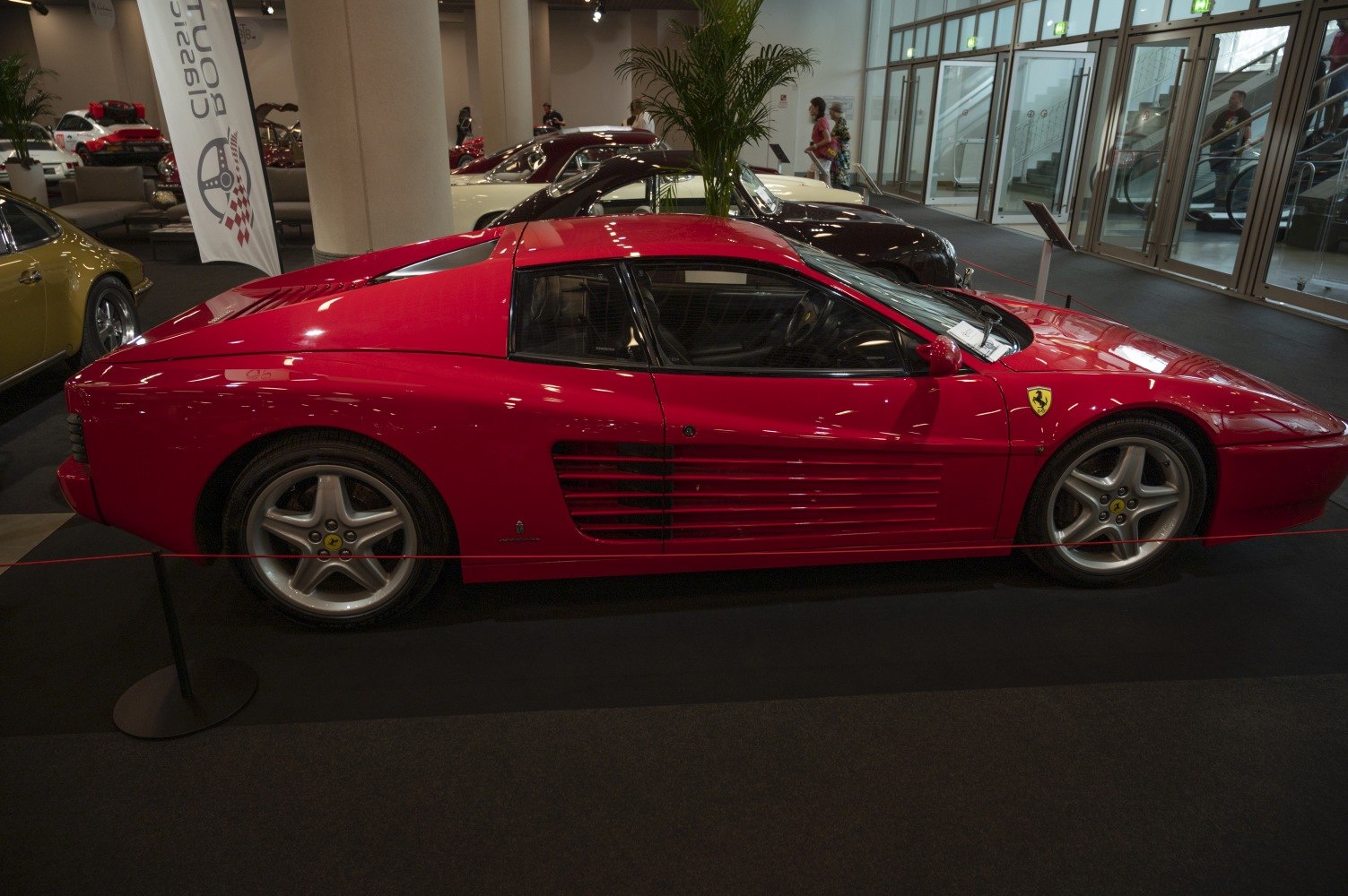 Side profile of a red sports car with distinctive side strakes and alloy wheels.