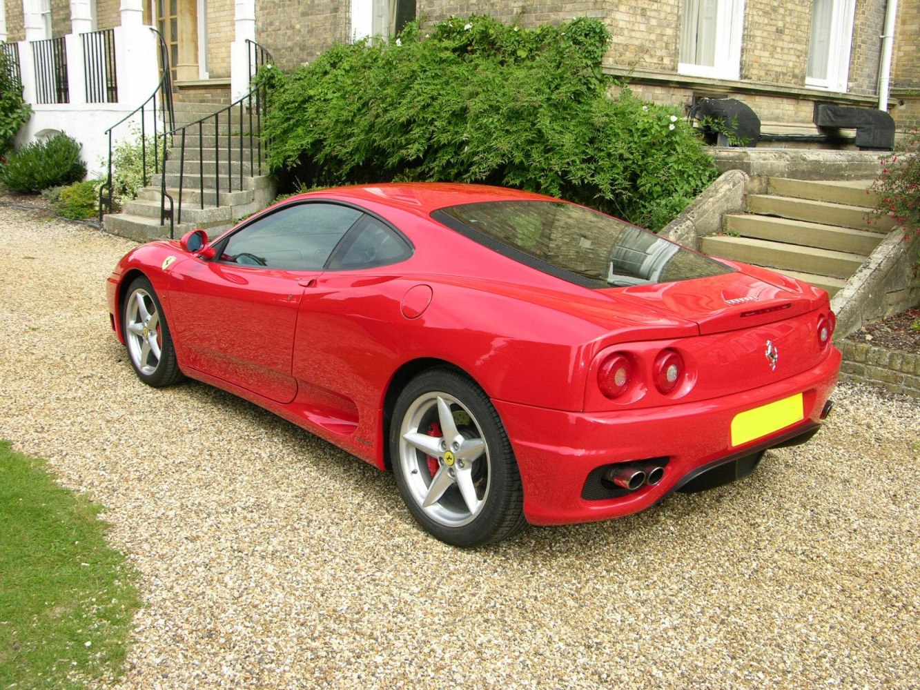 Red sports coupe rear-side view with quad exhaust and sleek design
