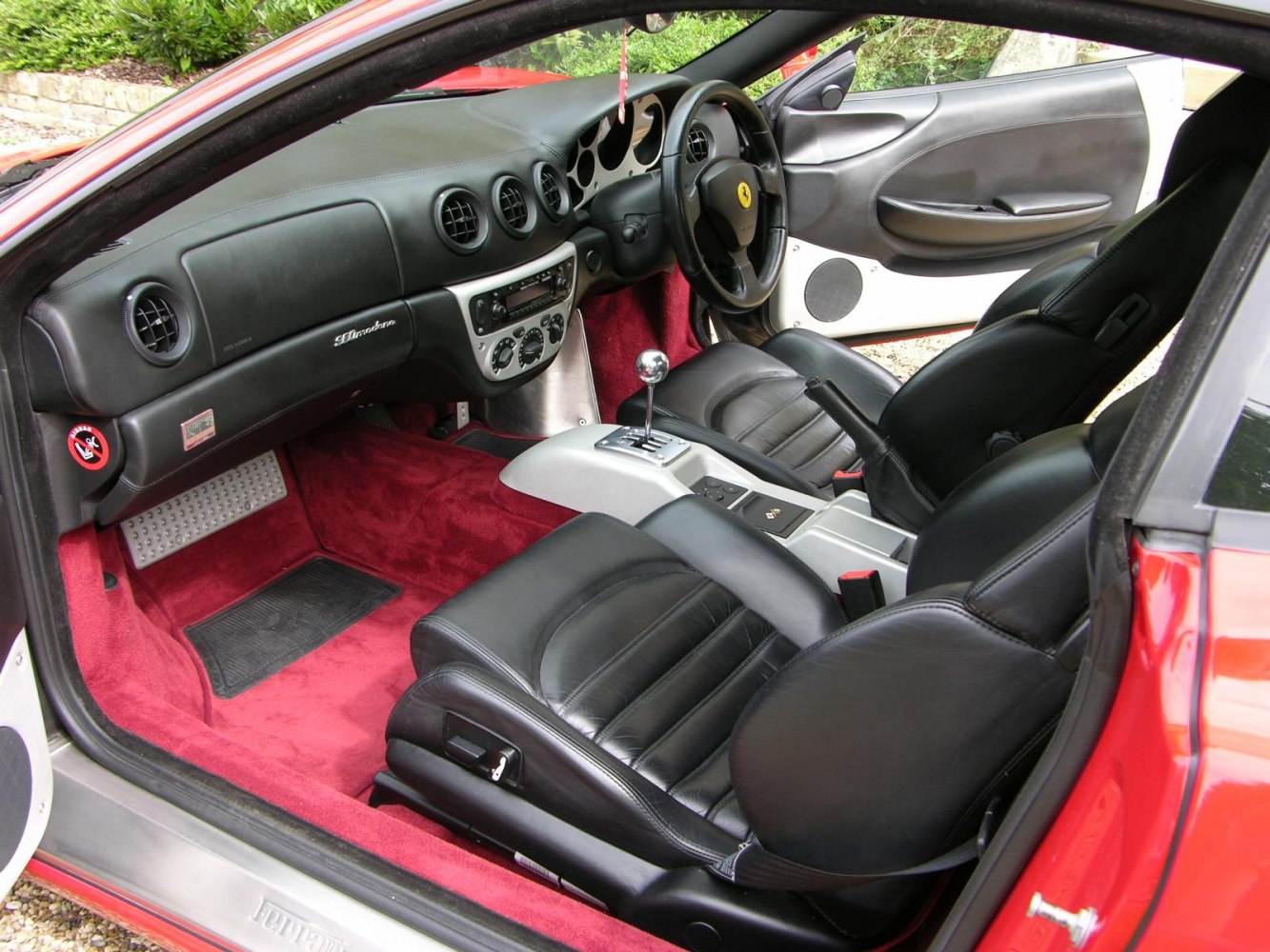 Black leather seats and manual gated shifter in a red carpeted interior