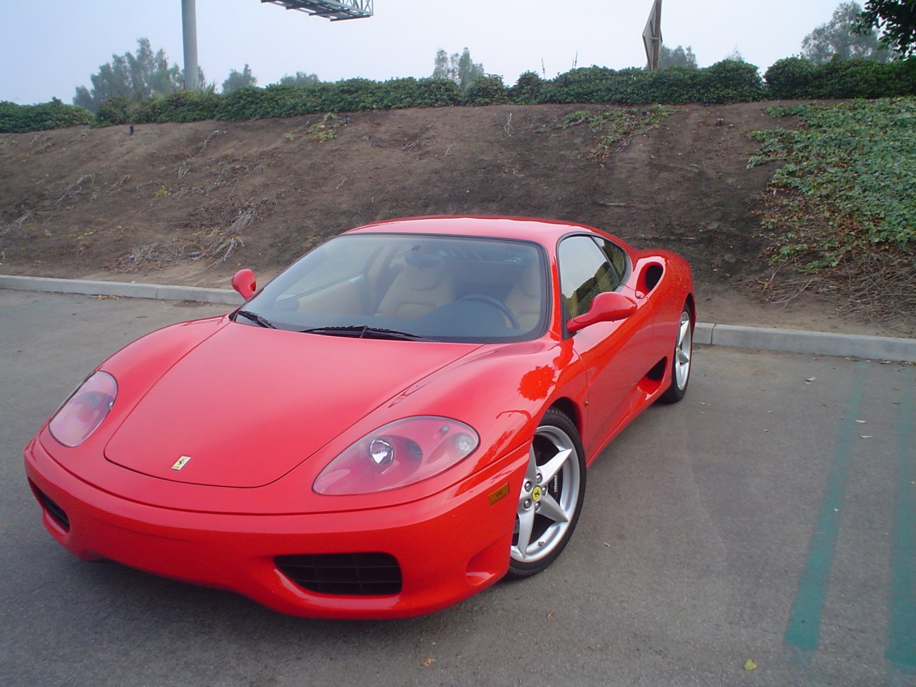 Red sports coupe with front headlights and alloy wheels.