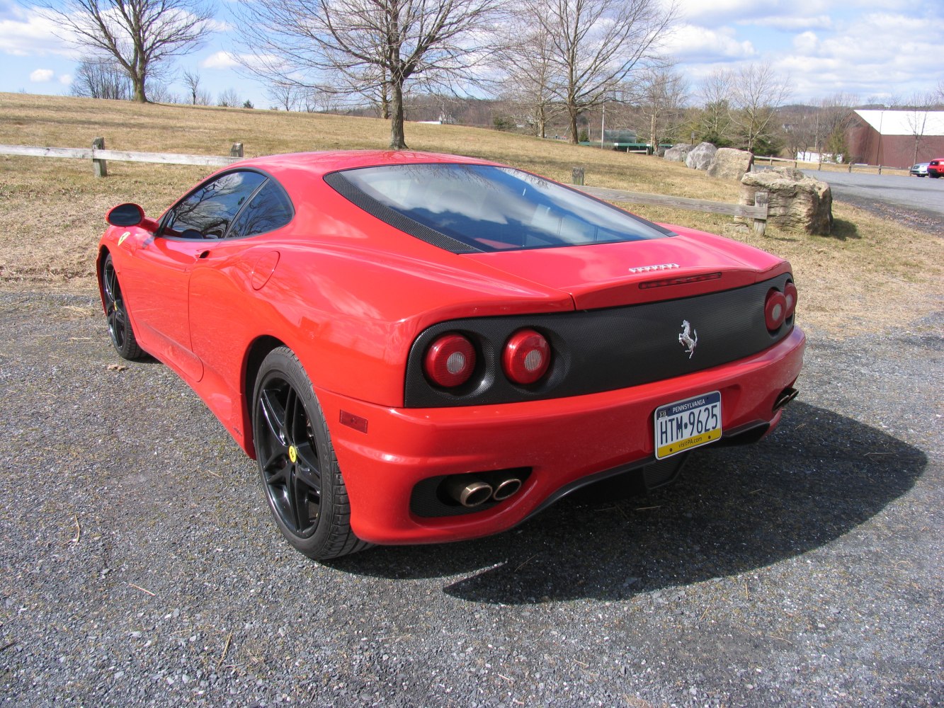 Rear of a red sports coupe with dual round tail lights and black alloy wheels