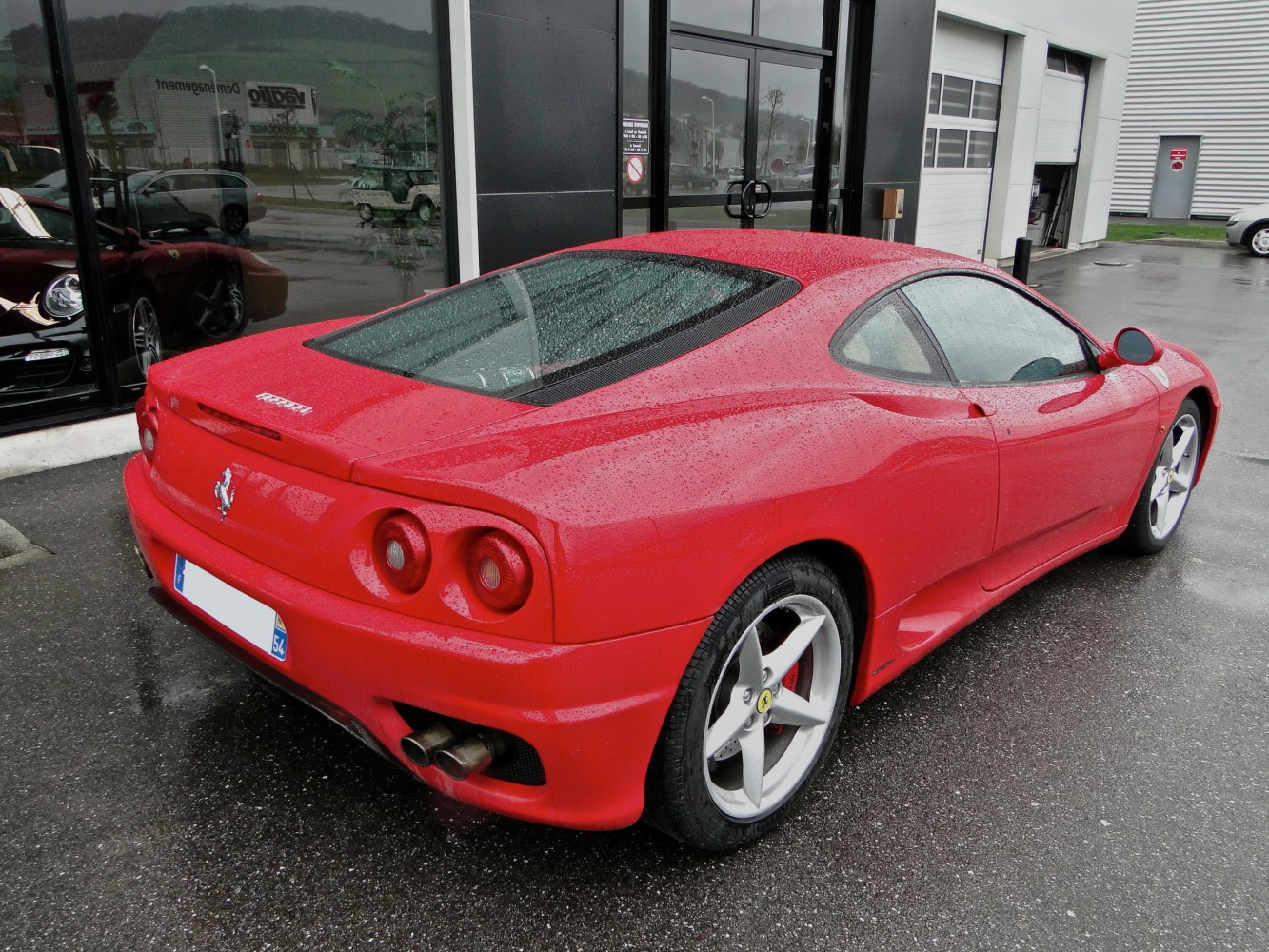 Rear side view of a red sports coupe with dual exhaust and round taillights