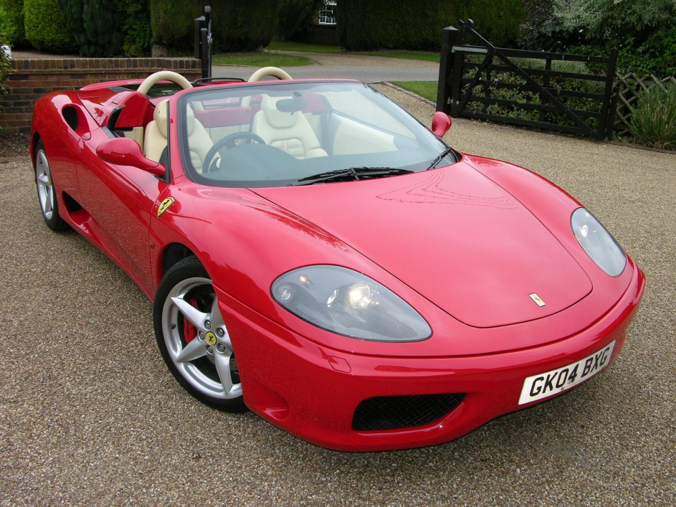 Red convertible with beige leather interior and sleek aerodynamic front design