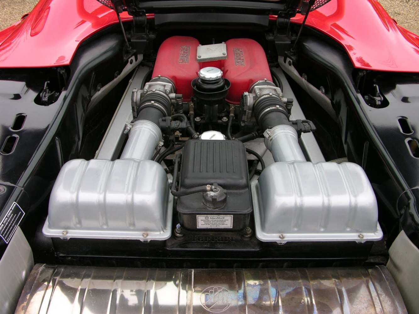 Detailed view of mid-mounted V8 engine bay with red intake manifold and twin silver air filters