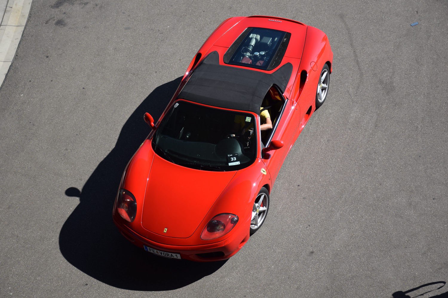 Red convertible sports car with visible mid-engine through glass top.