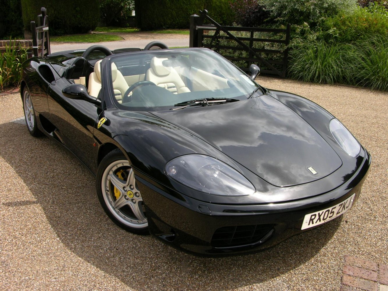 Black convertible sports car with beige leather seats and alloy wheels.