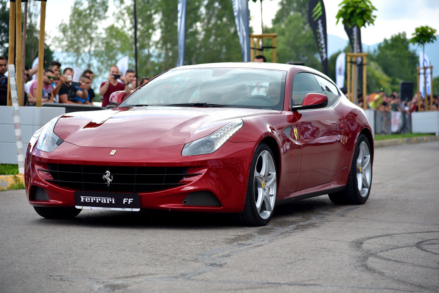 Front-side view of a sleek red sports car with aerodynamic curves and distinctive grille