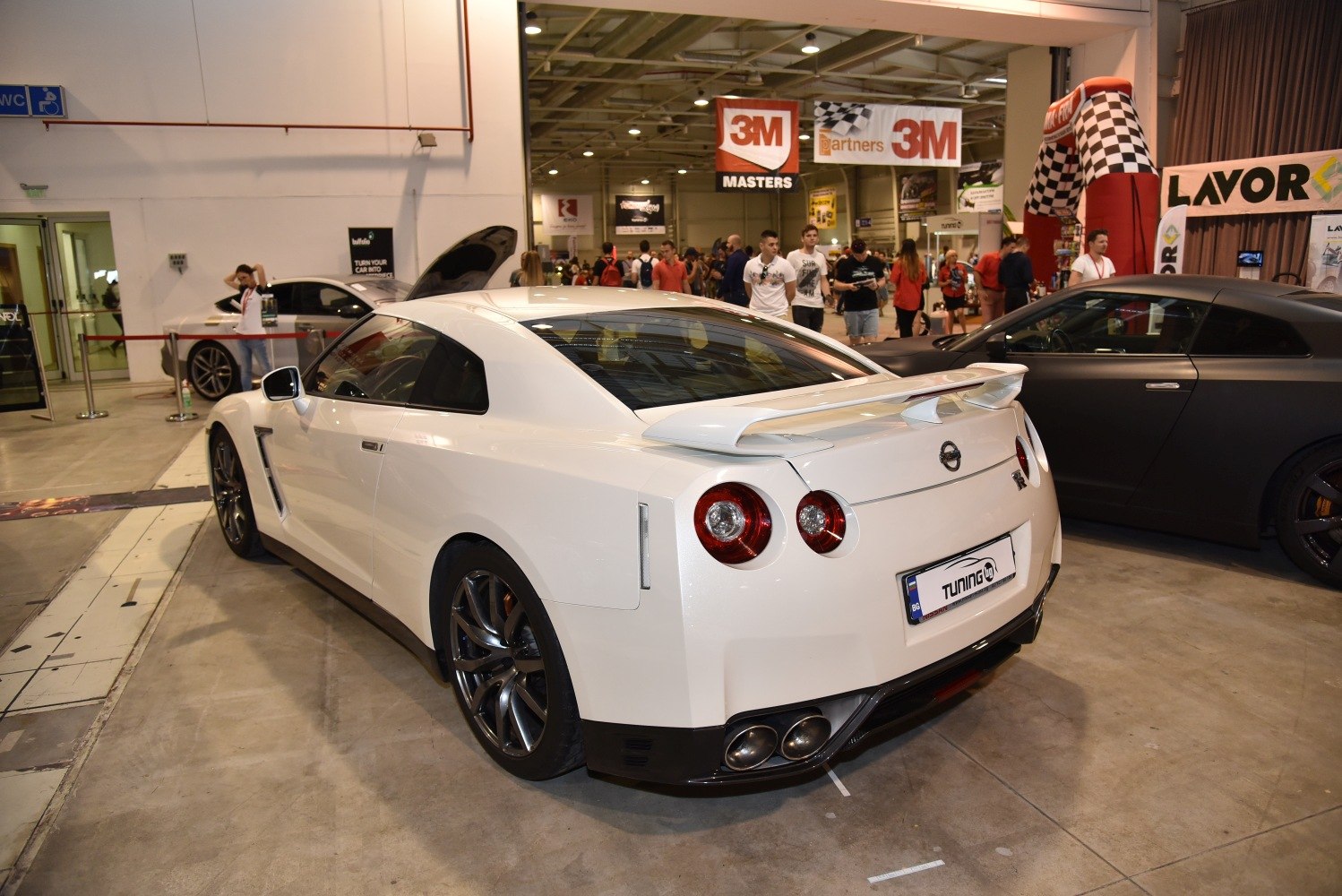 Rear view of a white sports coupe highlighting spoiler and quad exhaust