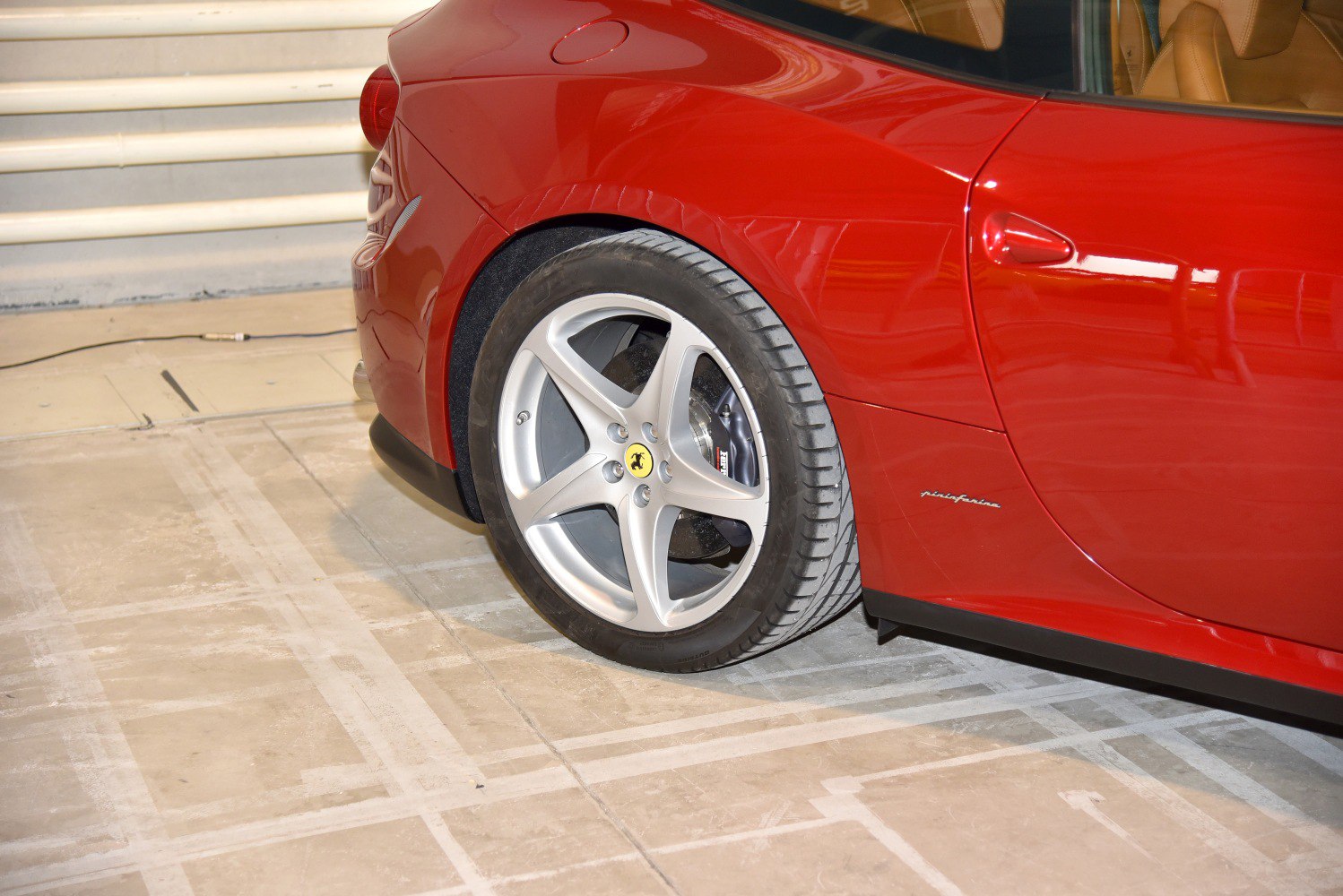 Rear wheel, alloy rim, tire, and Pininfarina badge on car side panel