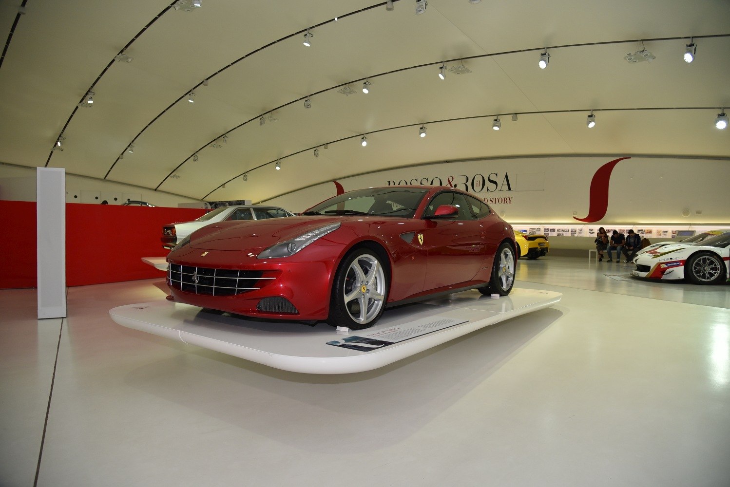 Front and side view of red luxury sports car with distinctive grille and curved roofline.