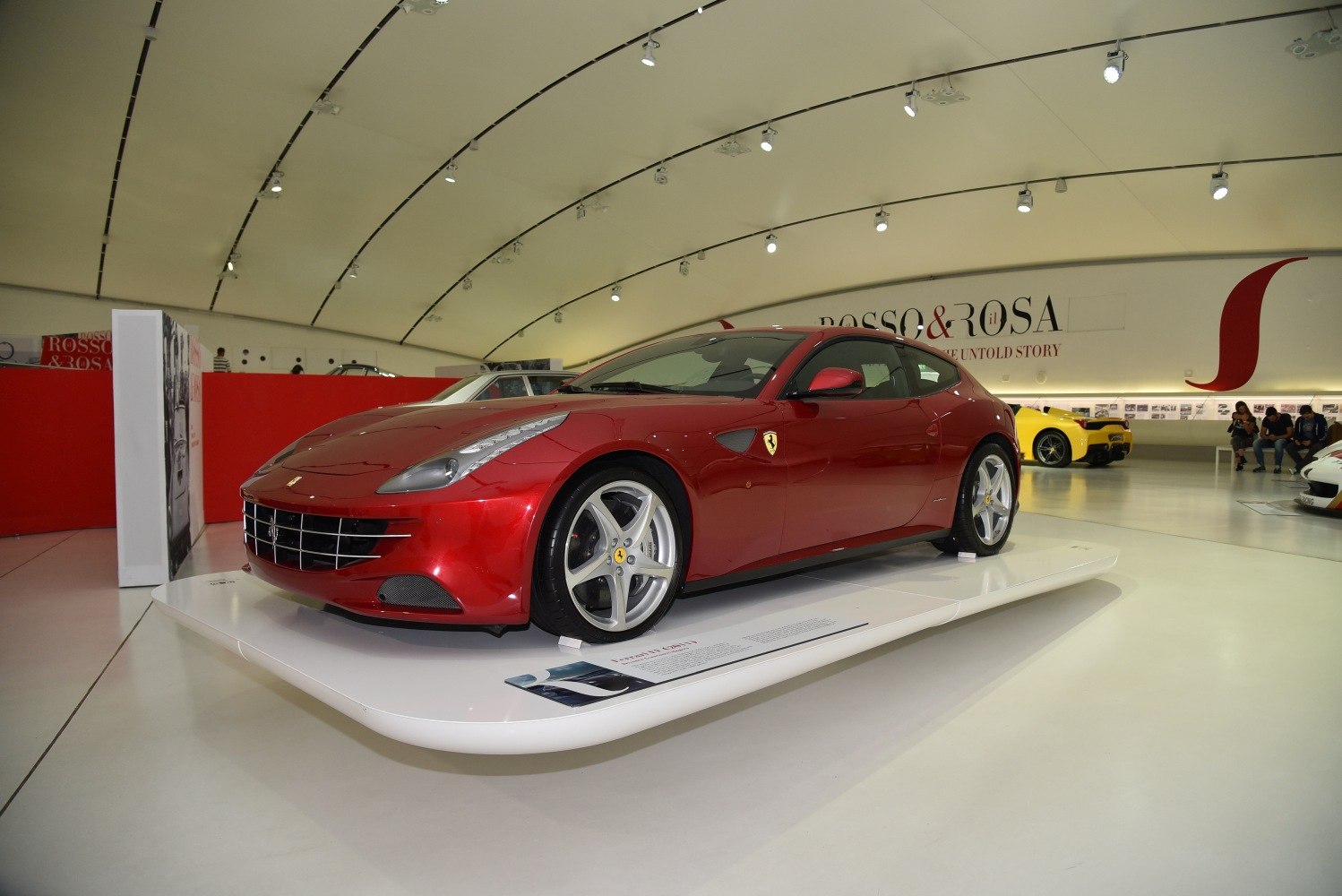 Red luxury four-seater sports coupe with distinctive front grille on display platform