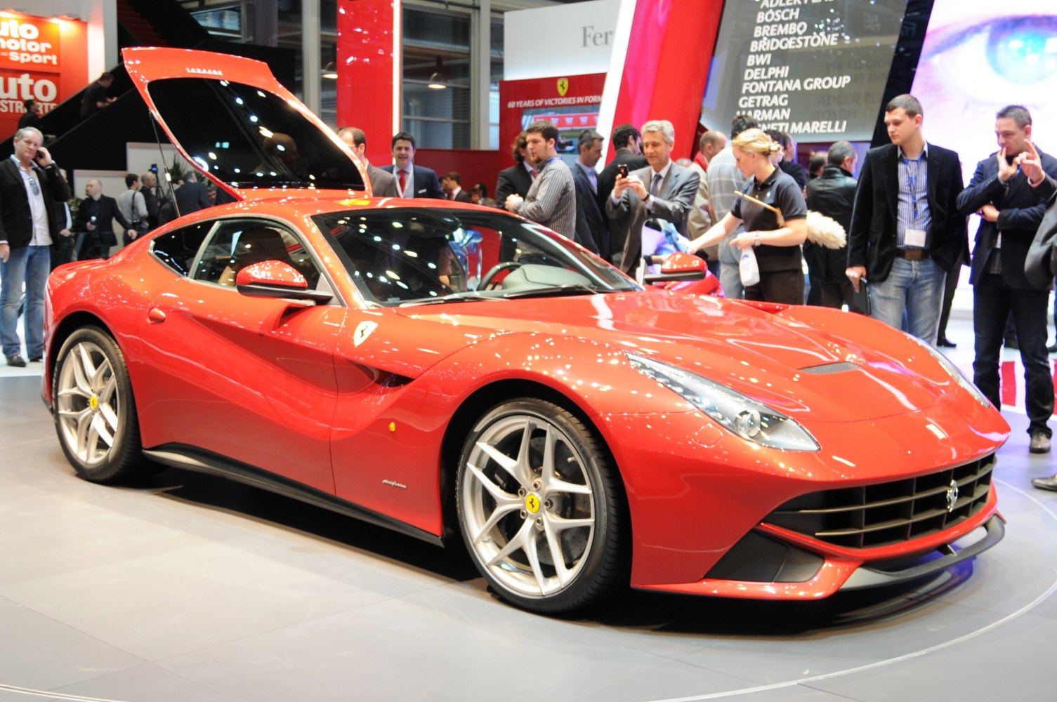 Front side view of red sports car with open hood and alloy wheels
