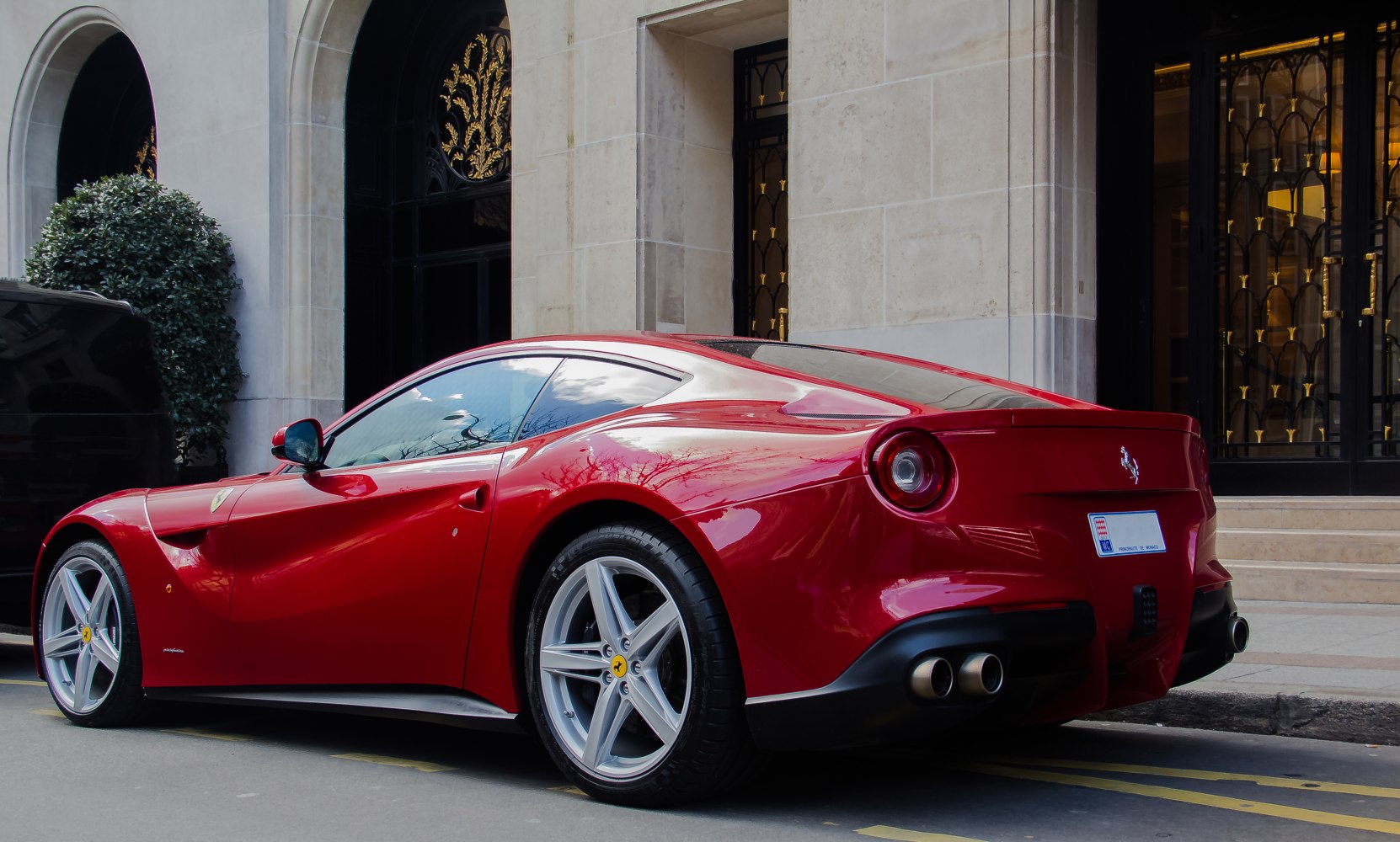Red luxury coupe with sleek aerodynamic side and dual exhausts at rear