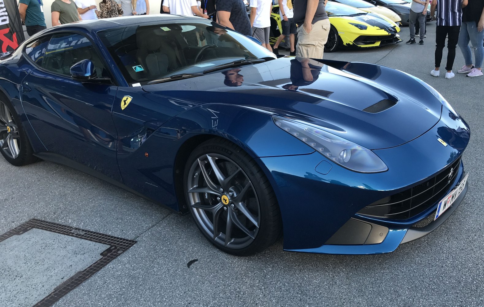 Aerodynamic headlights and sporty alloy wheels on blue Ferrari F12 Berlinetta front view