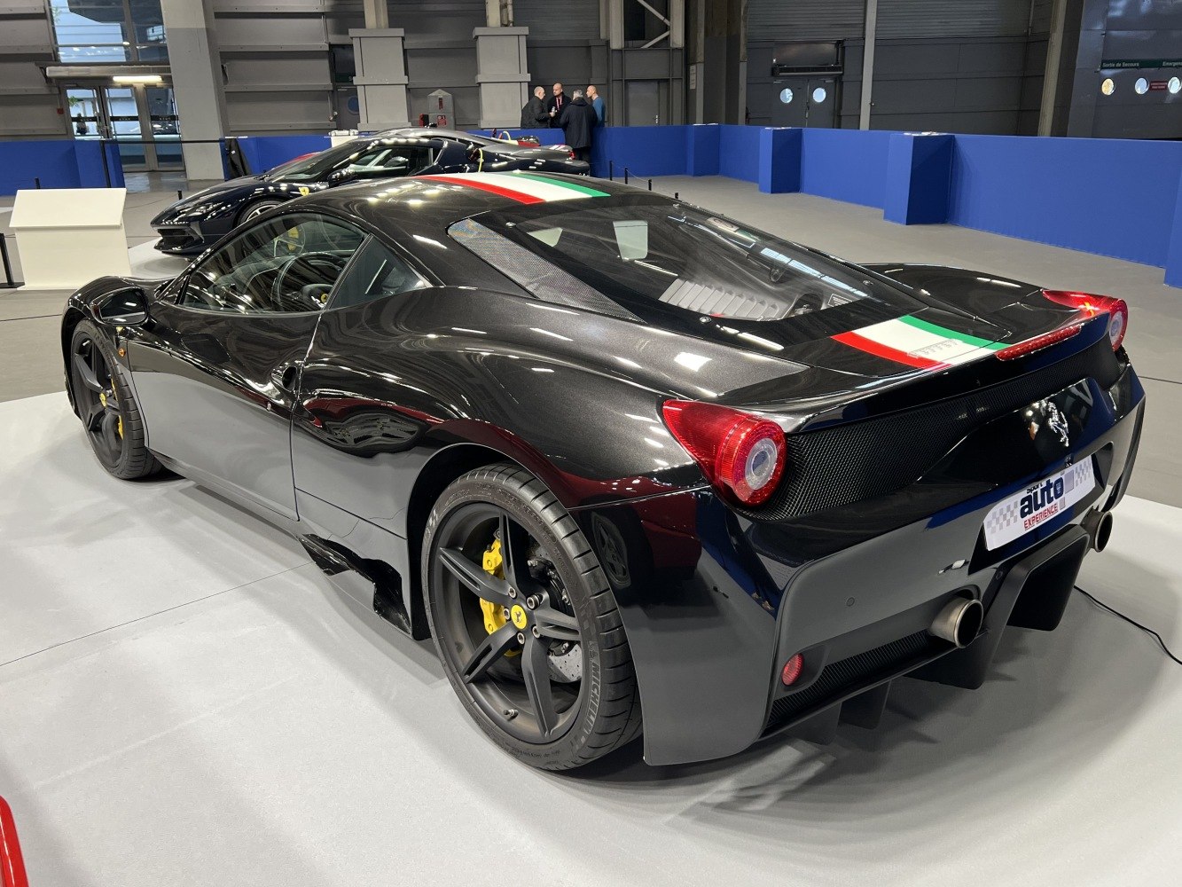 Rear and side view of black sports car with Italian flag roof stripe and distinctive tail lights.