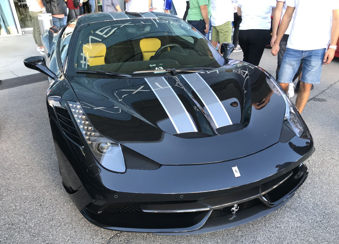 Front view of black Ferrari 458 Speciale with racing stripes and yellow seats