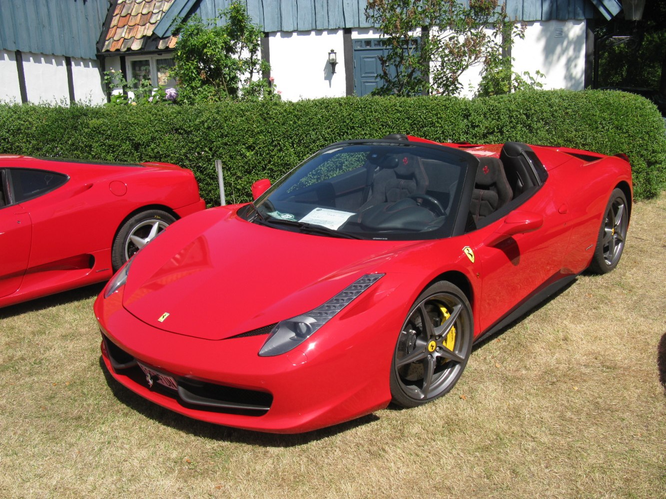 Front side view of a red convertible sports coupe with distinctive headlights and racing wheels.