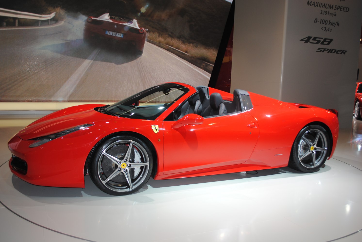 Red convertible sports car with sleek aerodynamic side profile and open roof.