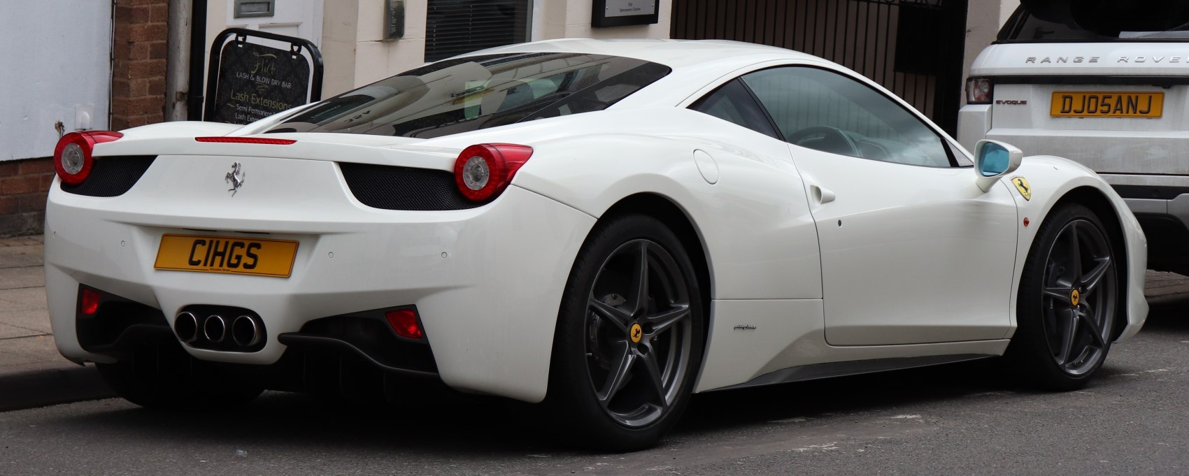 Rear and side view of white sports car with triple exhaust