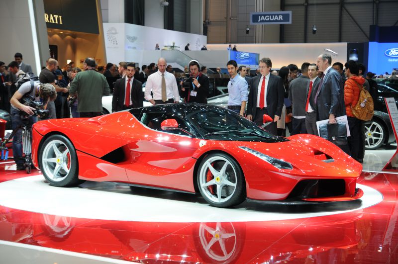Red hybrid supercar with aerodynamic shape and alloy wheels on display