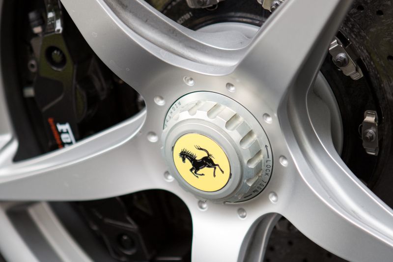Close-up of a silver alloy wheel with prancing horse emblem and carbon ceramic brake disc