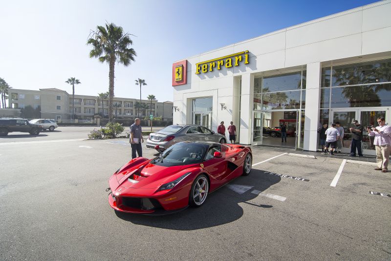 Front and side view of red Ferrari LaFerrari parked outdoors near dealership