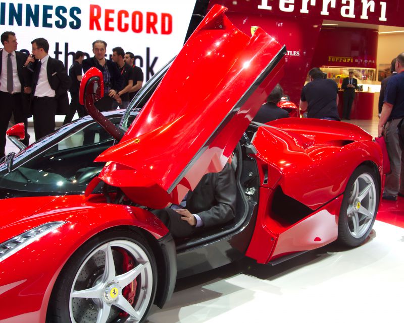 Red supercar with butterfly doors open at auto show