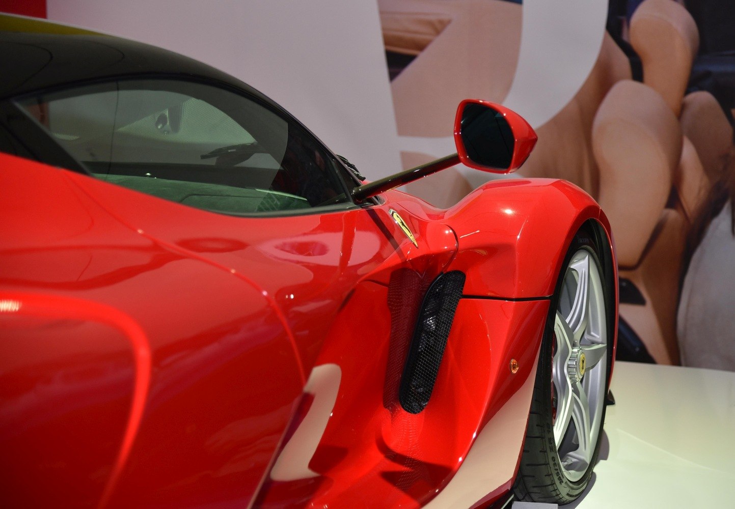 Red car side air intake, aerodynamic panel, alloy wheel, and uniquely shaped side mirror.