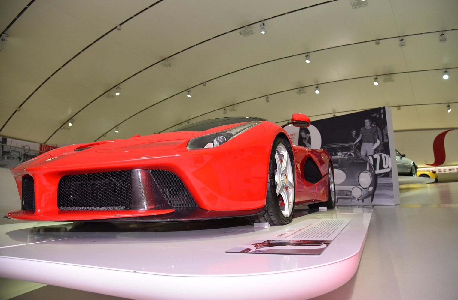 Red sports car front grille and side aerodynamic design with alloy wheels.