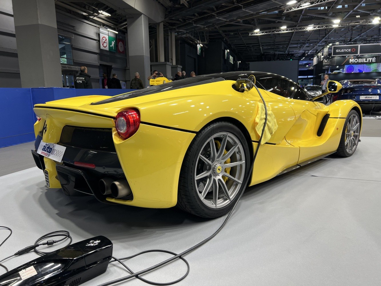 Rear-side of yellow hybrid sports car with charging cable