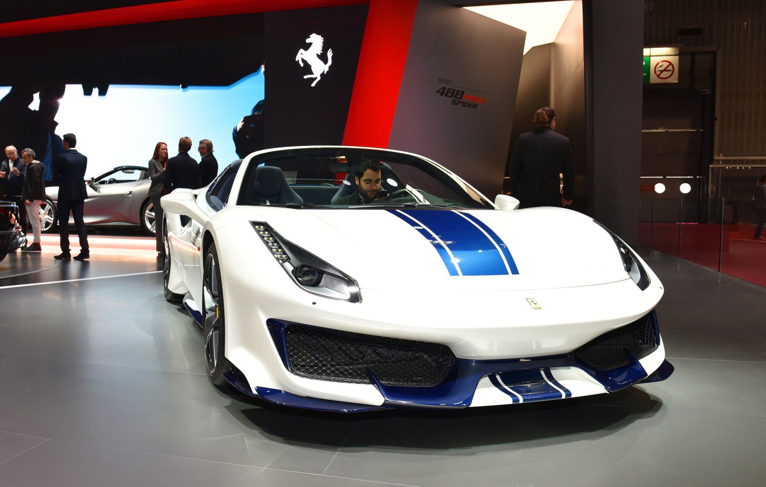 White convertible with blue racing stripes front view, aggressive aerodynamic design.
